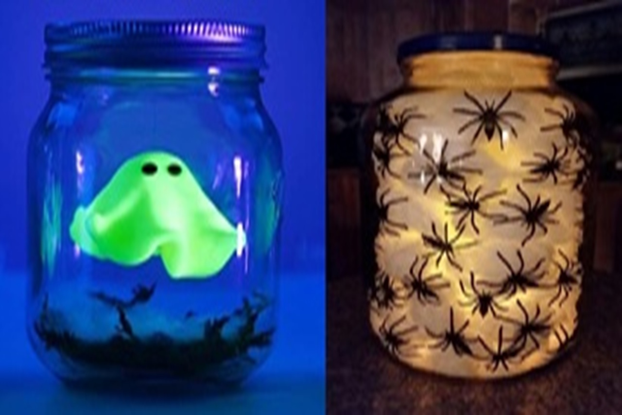glow in the dark cut out ghost in a jar and black plastic spider rings in a glass jar lit from inside with a candle