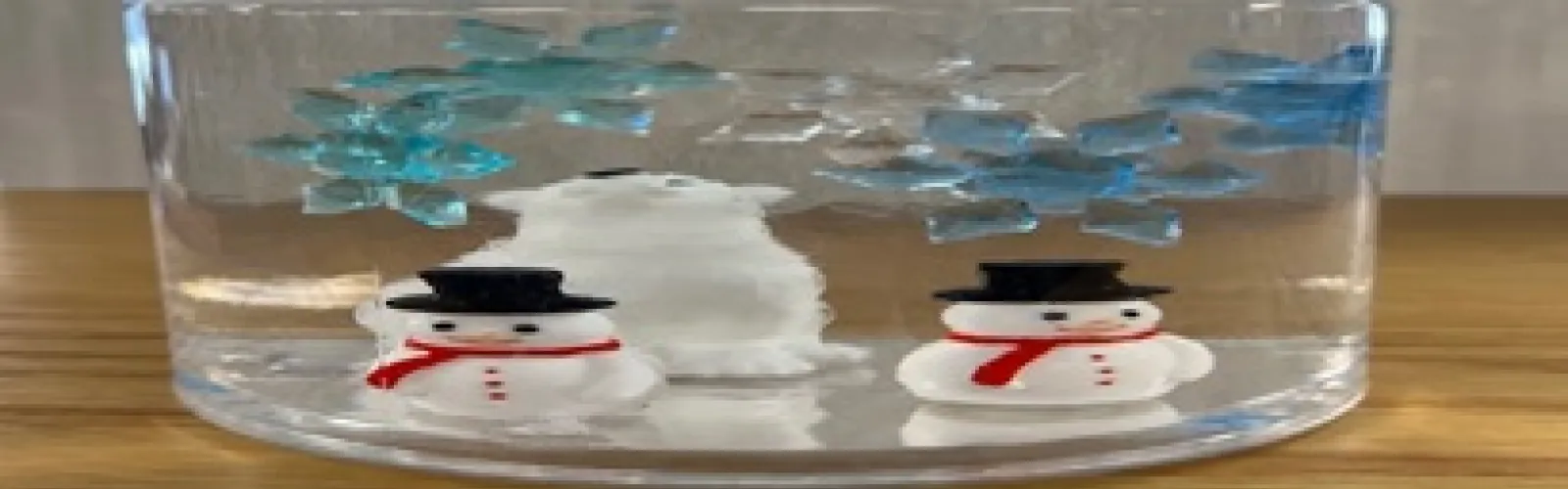 container with plastic polar bear and snowmen surrounded by "floating" snowflakes