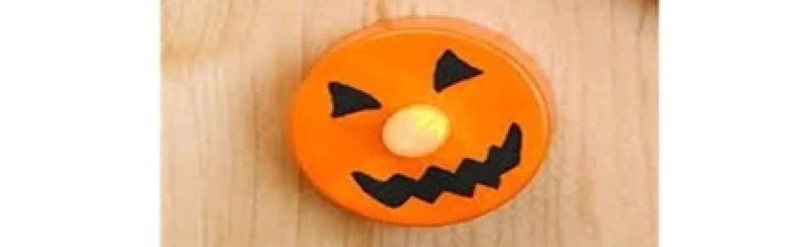 battery operated tea light colored orange with eyes and mouth drawn in black with light as nose